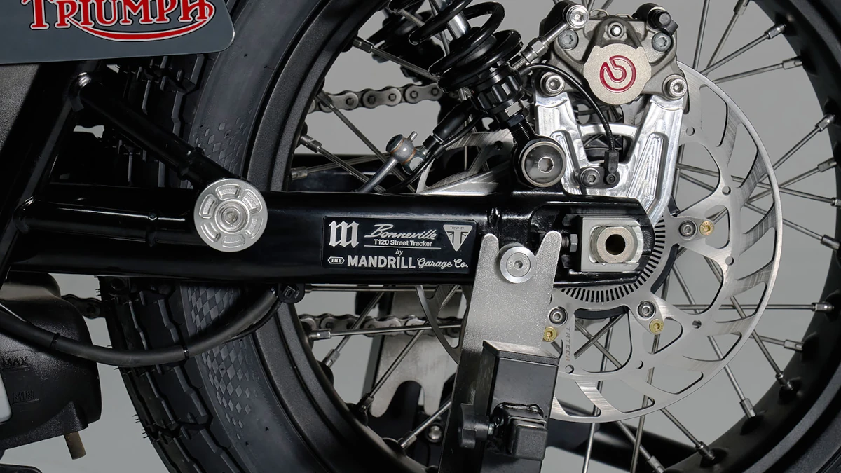 Triumph Bonneville T120 customizada con colores Rothmans, detalles en impresión 3D y diseño que mezcla lo vintage con tecnología moderna sobre fondo neutro.
