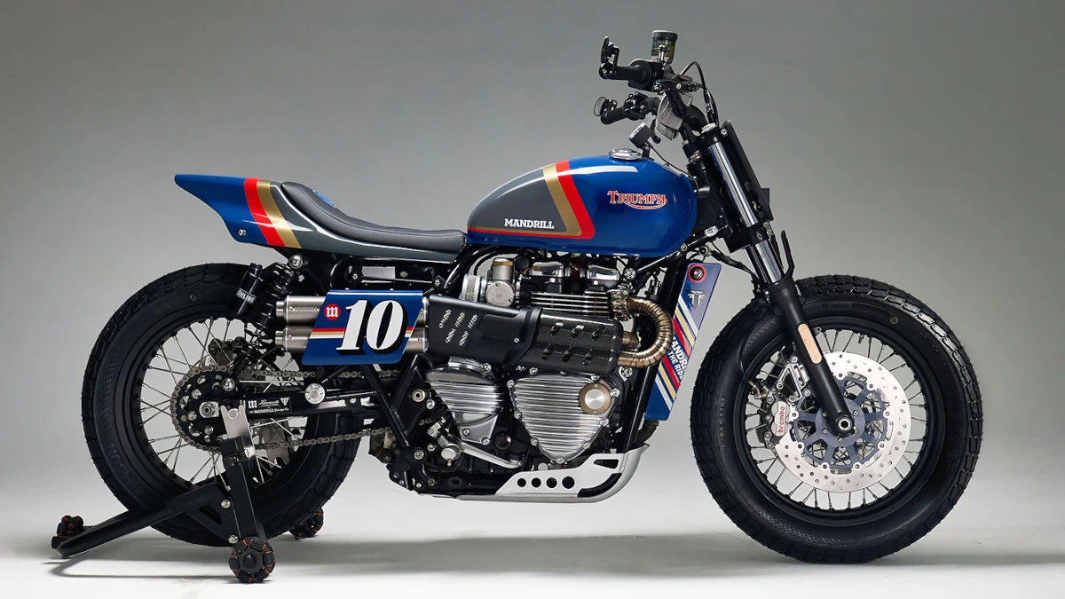 Triumph Bonneville T120 customizada con colores Rothmans, detalles en impresión 3D y diseño que mezcla lo vintage con tecnología moderna sobre fondo neutro.
