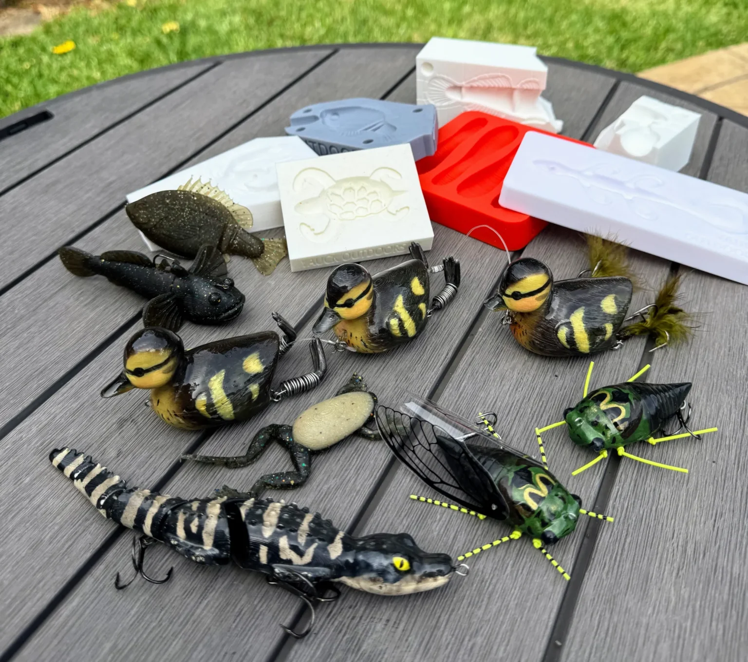 Señuelo de pesca impreso en 3D con forma de patito amarillo, mostrando detalles de diseño y anzuelo integrado, sobre fondo acuático.